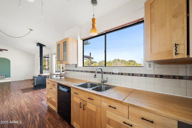 kitchen featuring tasteful backsplash, a wood stove, light brown cabinetry, a sink, and dishwasher