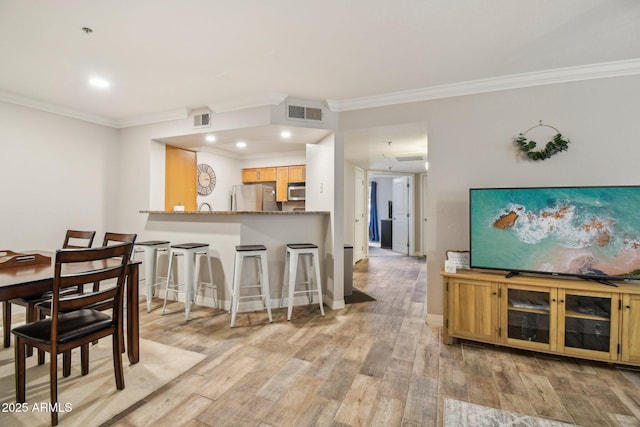 dining room with ornamental molding, light wood-style flooring, baseboards, and recessed lighting