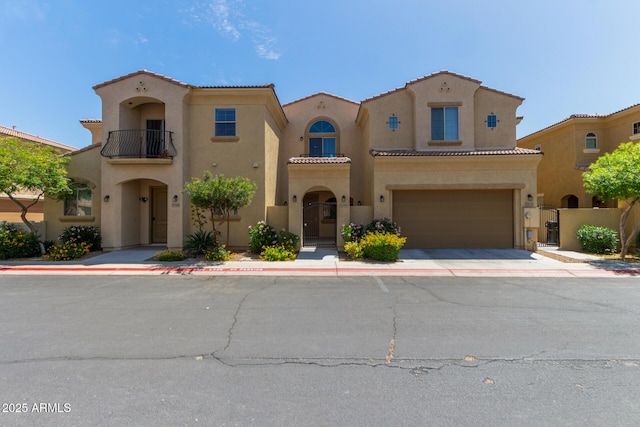 mediterranean / spanish-style home featuring a balcony, driveway, an attached garage, stucco siding, and a tile roof