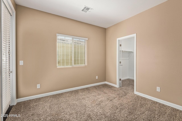 unfurnished bedroom with a closet, baseboards, visible vents, a spacious closet, and carpet floors