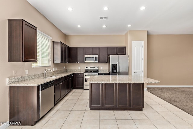 kitchen with a sink, stainless steel appliances, dark brown cabinetry, visible vents, and a kitchen island