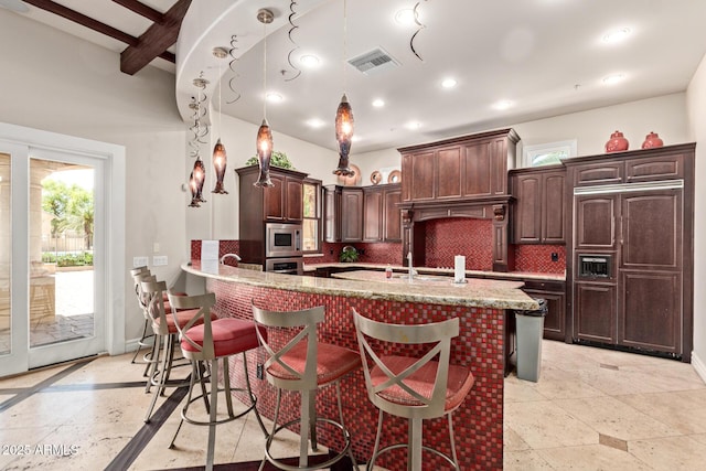 kitchen featuring stainless steel appliances, tasteful backsplash, a kitchen bar, and plenty of natural light