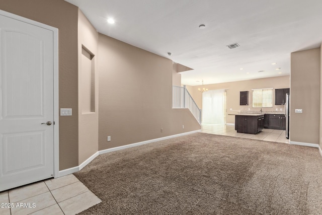 unfurnished living room with light tile patterned floors, light carpet, visible vents, baseboards, and a chandelier