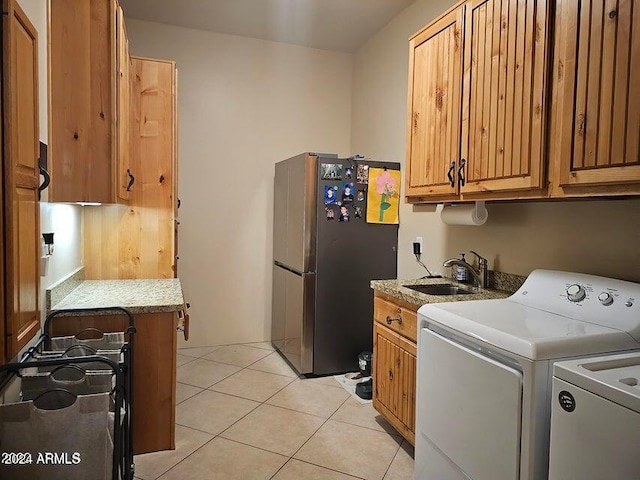 laundry area featuring light tile patterned flooring, washing machine and dryer, and sink