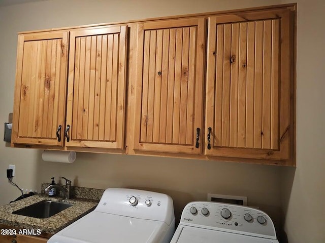 clothes washing area with cabinets, washing machine and dryer, and sink