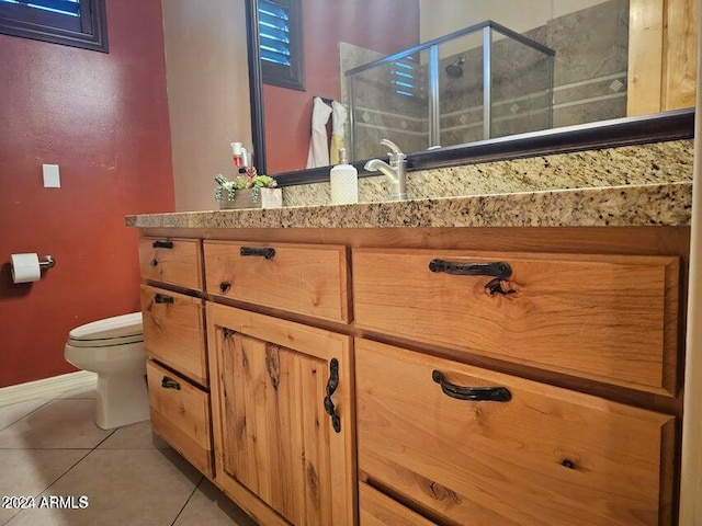 bathroom featuring tile patterned flooring, vanity, a shower with door, and toilet