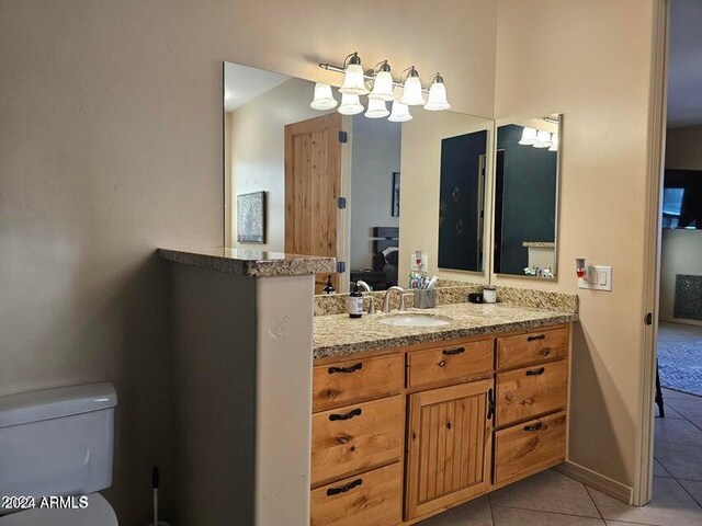 bathroom featuring tile patterned flooring, vanity, toilet, and a notable chandelier