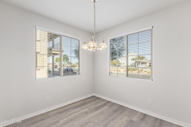 spare room featuring a notable chandelier and wood-type flooring