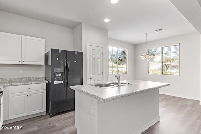 kitchen with white cabinetry, sink, black refrigerator with ice dispenser, a kitchen island with sink, and light wood-type flooring