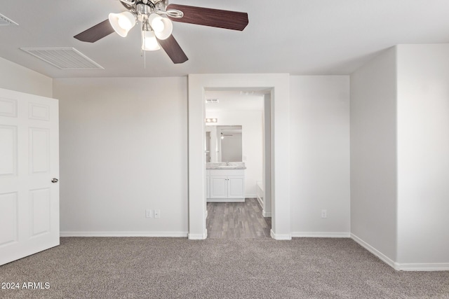 unfurnished bedroom with light colored carpet, ensuite bath, and ceiling fan