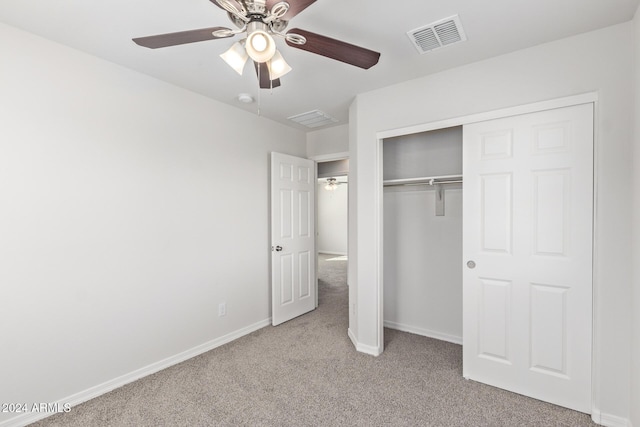 unfurnished bedroom featuring ceiling fan, light colored carpet, and a closet