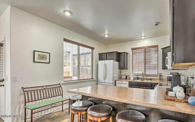 2600 W Old Linden Rd, Show Low, AZ 85901 - kitchen featuring white appliances, a peninsula, a kitchen bar, a sink, and light countertops