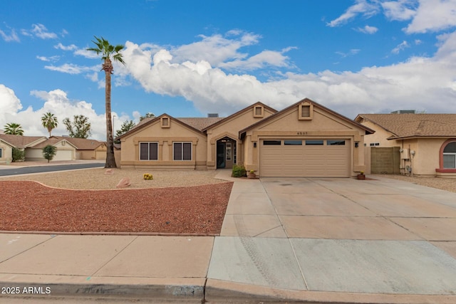 view of front of home with concrete driveway, fence, a garage, and stucco siding