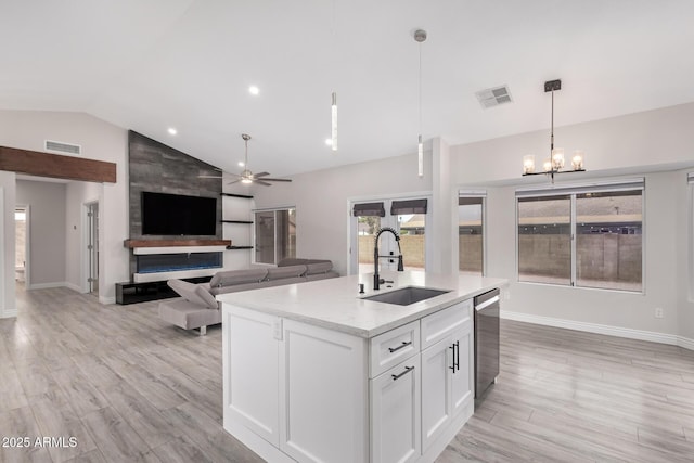 kitchen with ceiling fan with notable chandelier, a sink, stainless steel dishwasher, white cabinets, and lofted ceiling