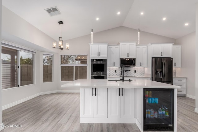 kitchen featuring beverage cooler, visible vents, a sink, light countertops, and appliances with stainless steel finishes