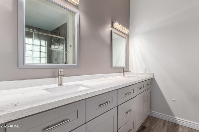 bathroom with double vanity, a stall shower, and a sink