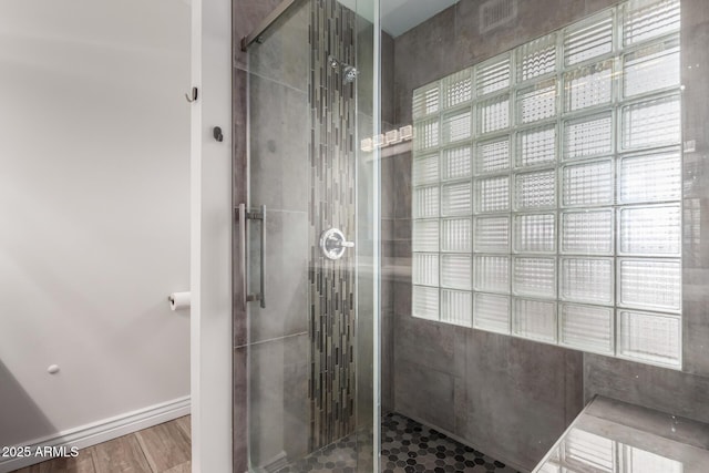 full bath featuring a stall shower, baseboards, and wood finished floors