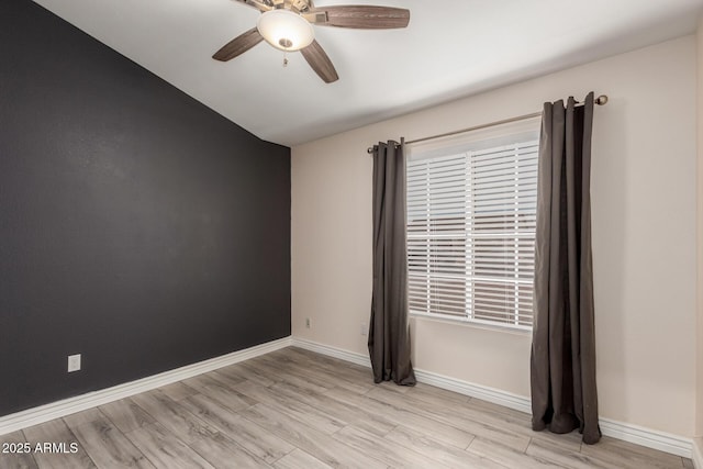 spare room featuring baseboards, light wood-type flooring, and ceiling fan