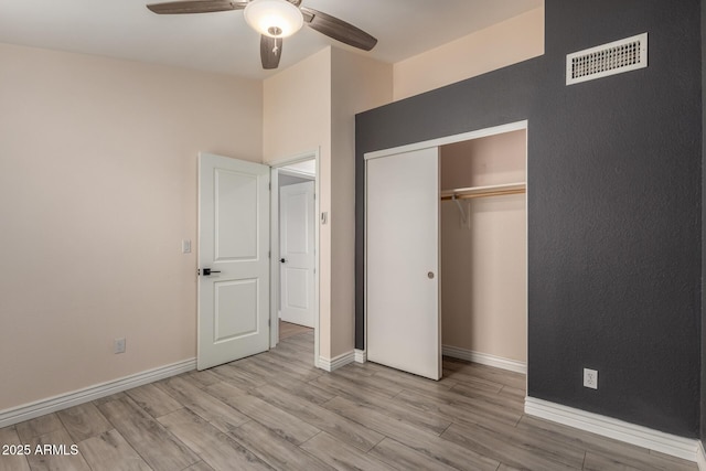 unfurnished bedroom with light wood finished floors, visible vents, a closet, and baseboards