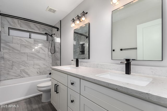 bathroom featuring visible vents, double vanity, a sink, shower / bathing tub combination, and toilet