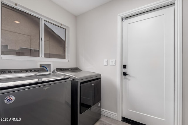 laundry area with laundry area, baseboards, light wood-type flooring, and washer and clothes dryer