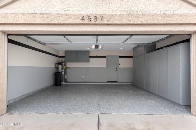 garage featuring baseboards, a garage door opener, and water heater