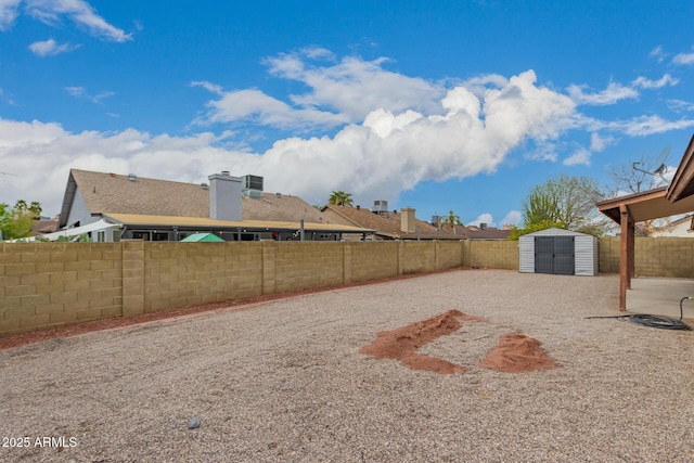 view of yard featuring an outbuilding, a storage unit, and a fenced backyard