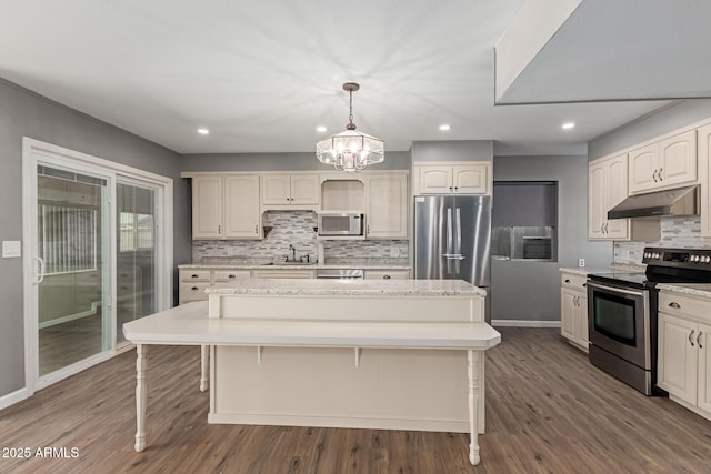 10001 W Caron Dr, Sun City, AZ 85351 - kitchen featuring stainless steel appliances, under cabinet range hood, a sink, a center island, and decorative backsplash