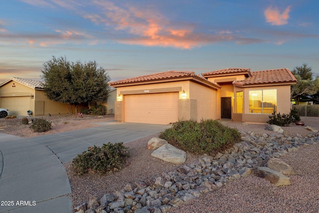 mediterranean / spanish house with an attached garage, fence, a tile roof, concrete driveway, and stucco siding