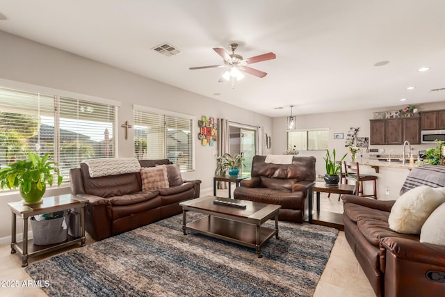 living room featuring ceiling fan, light tile patterned floors, and sink