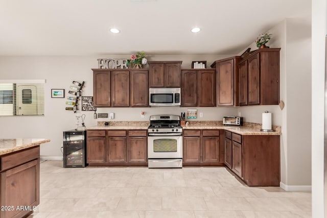 kitchen featuring white range with gas stovetop, dark brown cabinets, light stone counters, and beverage cooler