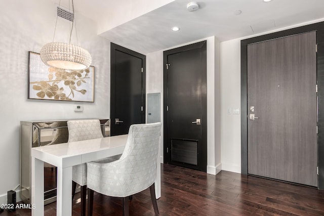 dining space featuring dark hardwood / wood-style flooring and an inviting chandelier