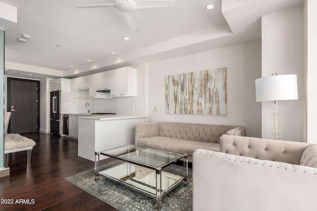 living room featuring a tray ceiling, ceiling fan, dark hardwood / wood-style flooring, and sink