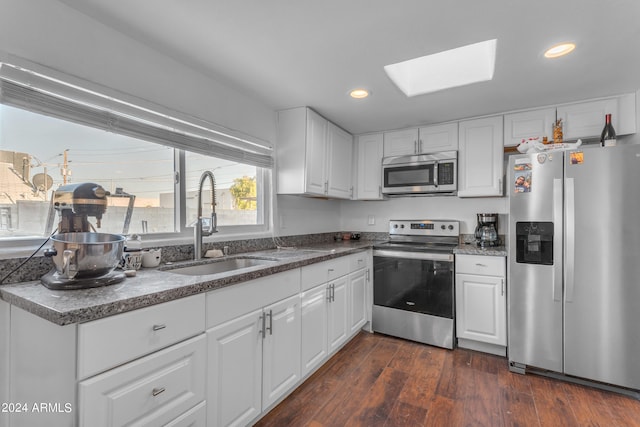 kitchen featuring appliances with stainless steel finishes, dark hardwood / wood-style flooring, a skylight, and sink