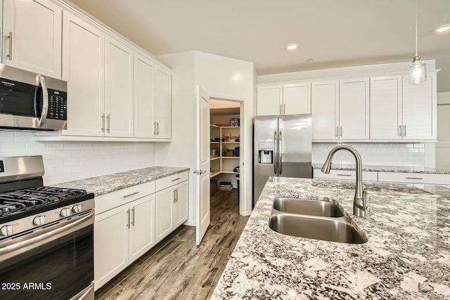 kitchen featuring light stone countertops, stainless steel appliances, white cabinets, and sink