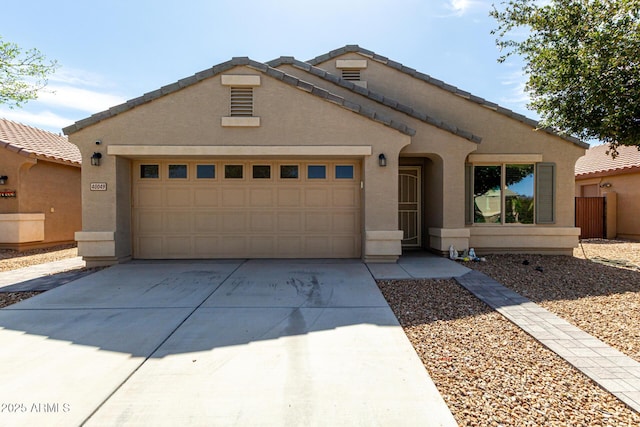 view of front of home with concrete driveway, an attached garage, a tile roof, and stucco siding