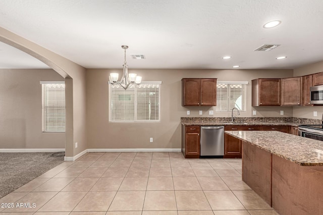 kitchen featuring light stone counters, visible vents, appliances with stainless steel finishes, and a sink