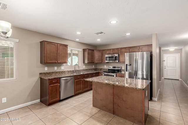 kitchen featuring dark stone countertops, baseboards, visible vents, a sink, and stainless steel appliances