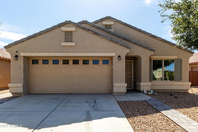 view of front of home with stucco siding, a tiled roof, concrete driveway, and a garage