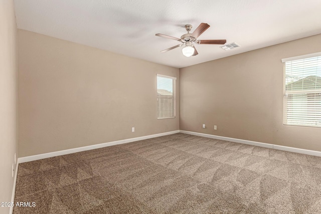 carpeted empty room featuring visible vents, ceiling fan, and baseboards