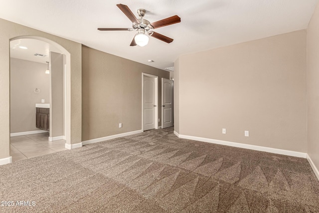 unfurnished bedroom with visible vents, arched walkways, carpet floors, and baseboards