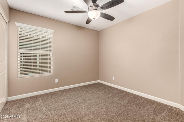 carpeted spare room with visible vents, baseboards, and a ceiling fan