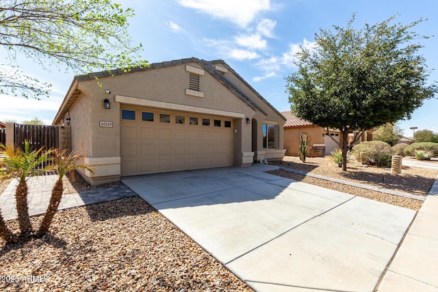 view of front of home with fence, a tiled roof, concrete driveway, stucco siding, and an attached garage