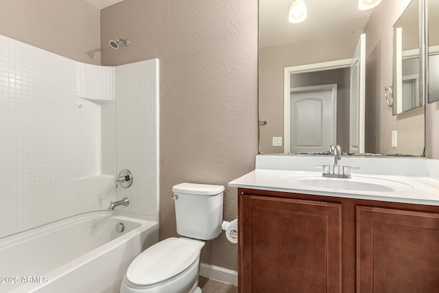 bathroom featuring vanity, baseboards, shower / bath combination, toilet, and a textured wall