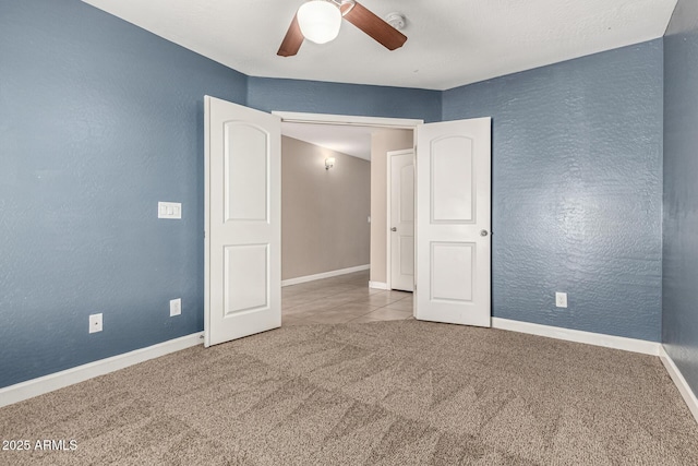 carpeted spare room with baseboards, ceiling fan, and a textured wall