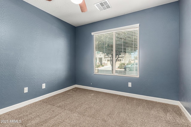 unfurnished room with visible vents, carpet, baseboards, ceiling fan, and a textured wall