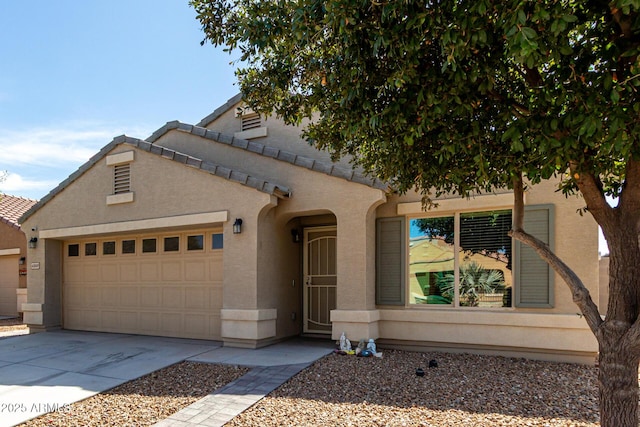 mediterranean / spanish-style home with concrete driveway, a tiled roof, an attached garage, and stucco siding