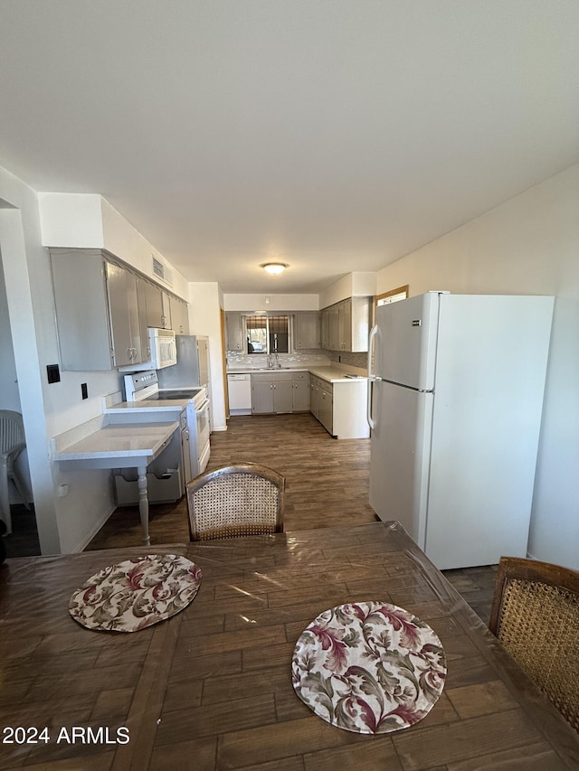 kitchen featuring white appliances, kitchen peninsula, dark wood-type flooring, and sink