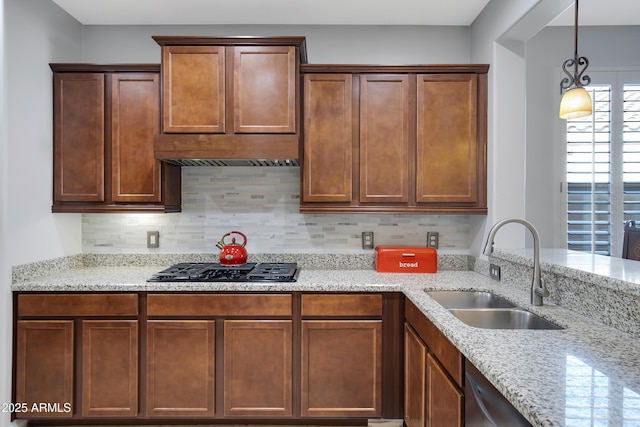 kitchen with sink, tasteful backsplash, light stone countertops, black gas stovetop, and custom exhaust hood