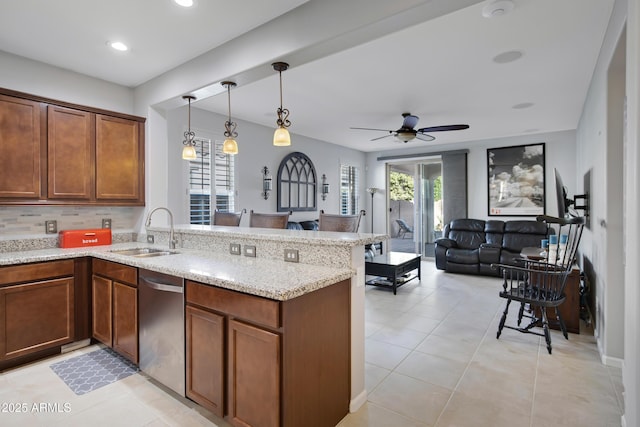 kitchen with decorative light fixtures, sink, stainless steel dishwasher, kitchen peninsula, and plenty of natural light